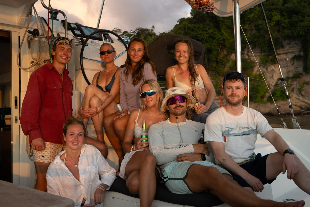 Group of crew members sitting together on deck at sunset