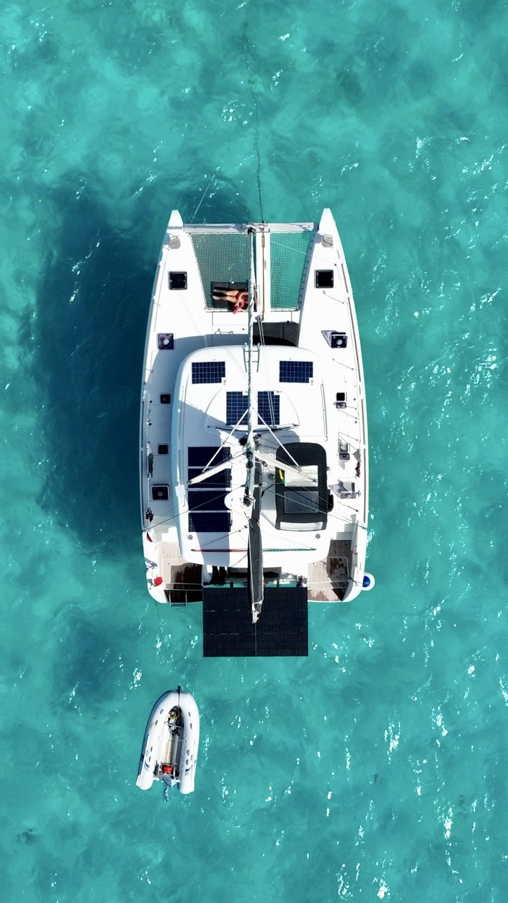 Aerial view of Laurelli at anchor, crew relaxing on the trampoline