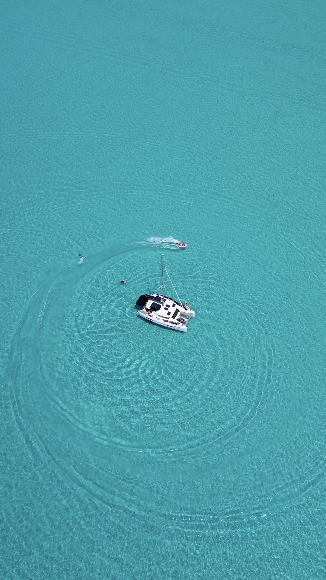 Laurelli anchored in shallow turquoise water with crew swimming nearby