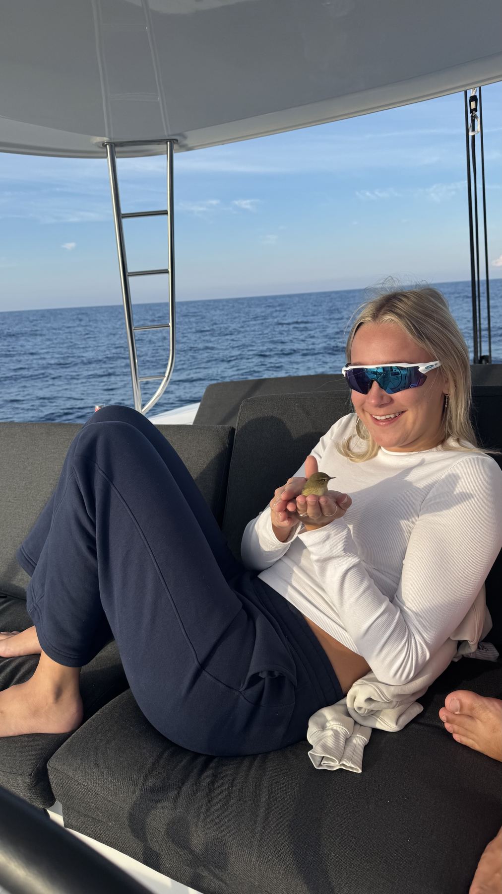 Ella holding a small bird that landed on the boat